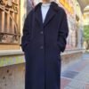 Μακρύ, μαύρο παλτό με γούνα στο γιακά και μεγάλα κουμπιά